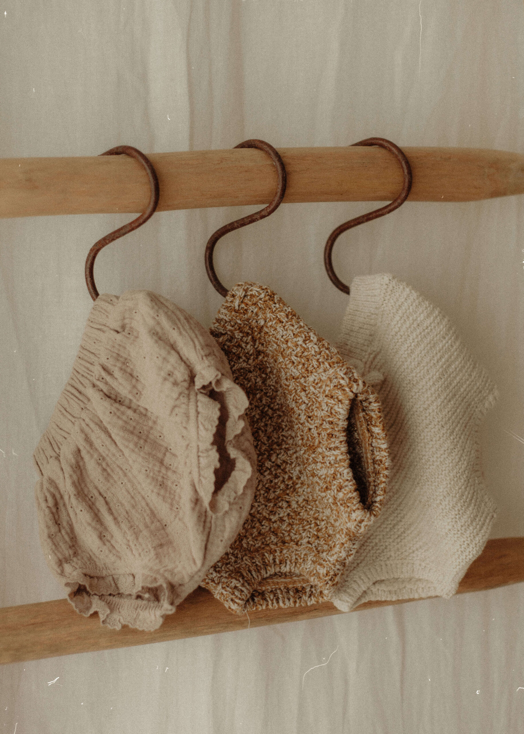 A selection of knitted baby bloomers, hanging from a wooden ladder in my cotswold photography studio